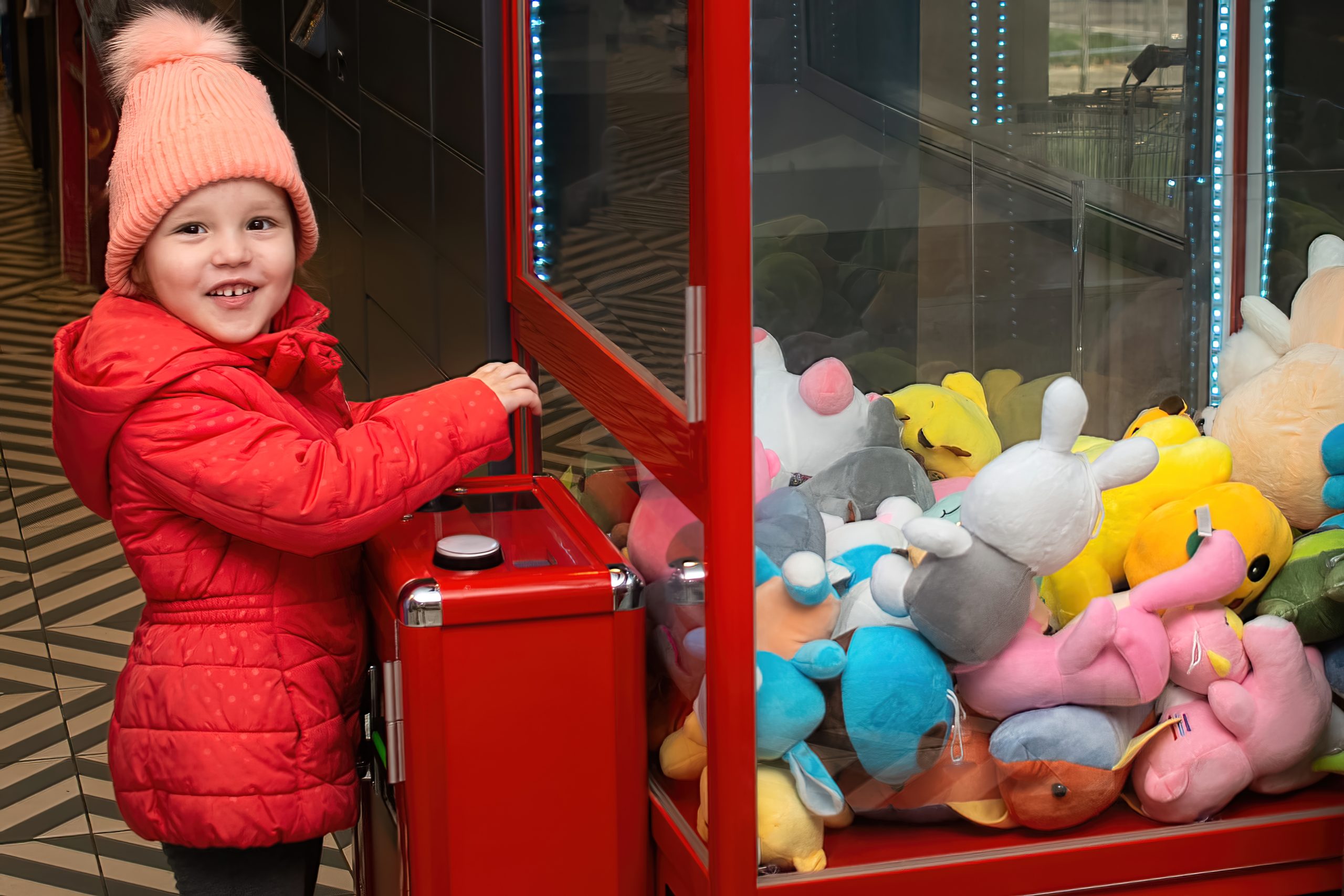 Une petite fille essaye d'attraper des peluches
